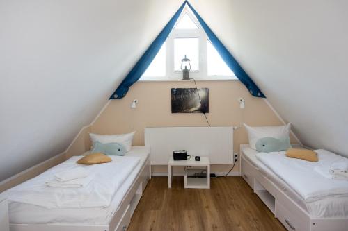 two beds in a attic room with a window at Premiumhaus Bodden und Mehr-Brise in Born