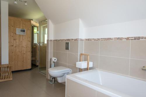 a bathroom with a toilet and a sink and a tub at Premiumhaus Bodden und Mehr-Brise in Born