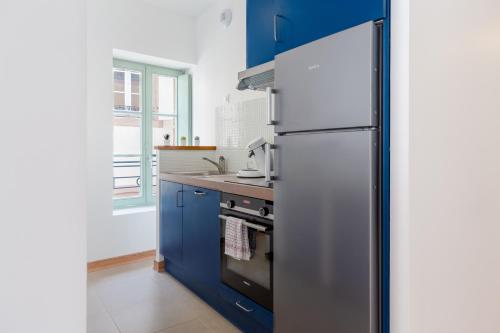 een keuken met blauwe kasten en een koelkast bij My Colmar Homes - Le XIII in Colmar
