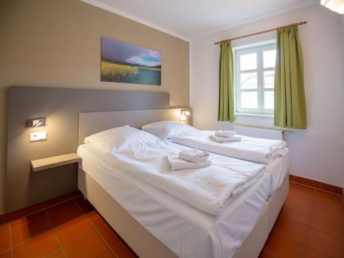 een slaapkamer met een groot wit bed en handdoeken bij Feriendorf Rugana - Komfort Appartement mit 1 Schlafzimmer und Terrasse B52 in Dranske