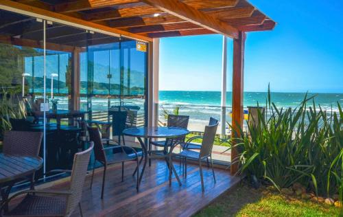 a patio with a table and chairs and the ocean at Pousada Vila Del Mare in Bombinhas