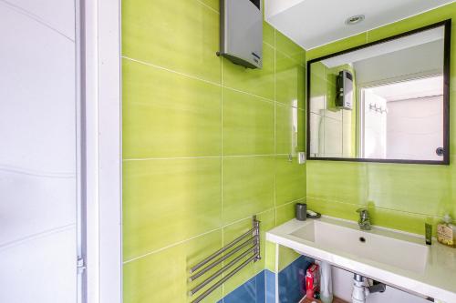 a green bathroom with a sink and a mirror at Primavéra in Sanary-sur-Mer