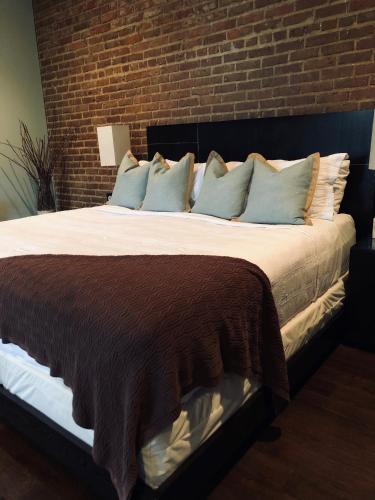 a bedroom with a large bed with a brick wall at Suites at 249 in Culpeper