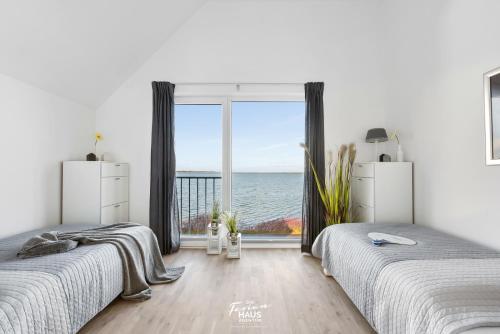 two beds in a bedroom with a view of the ocean at Slienblik in Olpenitz