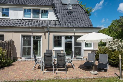 a group of chairs and an umbrella in front of a house at Premiumhaus Bodden und Mehr-Brise in Born