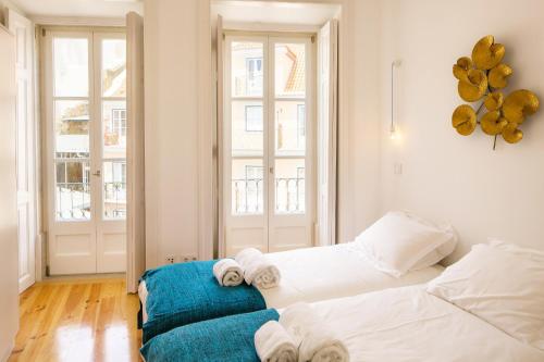 Habitación con 2 camas y sofá azul en Alfama Balcony River View 11 by Lisbonne Collection, en Lisboa