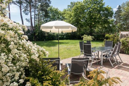 a patio with a table and chairs and an umbrella at Premiumhaus Bodden und Mehr-Brise in Born