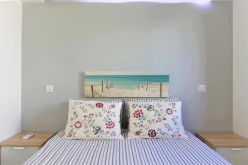 uma cama com duas almofadas e uma pintura de uma praia em Vila - Mar - Private outdoor Jacuzzi - wifi & airco - by bedzy em Albufeira