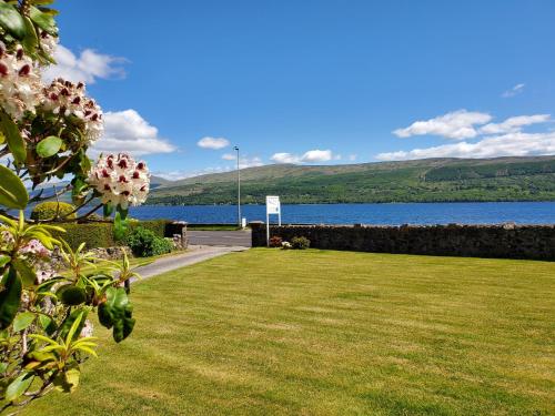 a lawn with a view of the water and mountains at Rudha-na-Craige in Inveraray