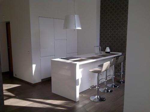 a white kitchen with a counter and stools at Central Apartment Palanga in Palanga