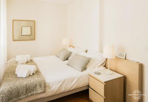 Schlafzimmer mit einem Bett mit weißer Bettwäsche und einem Nachttisch in der Unterkunft Modern and Comfort Apartment 25 by Lisbonne Collection in Lissabon