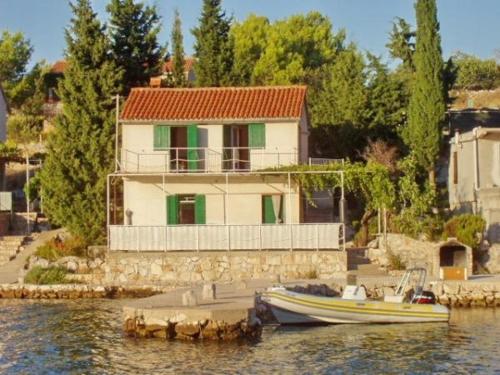 a house on the water with a boat in the water at Robinson House Zut (3467) in Bizikovica