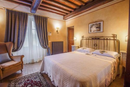 a bedroom with a bed and a chair and a window at Tenuta Guardastelle - Agriturismo and vineyard in San Gimignano