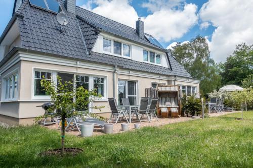 a house with a patio and chairs in the yard at Premiumhaus Bodden und Mehr-Brise in Born