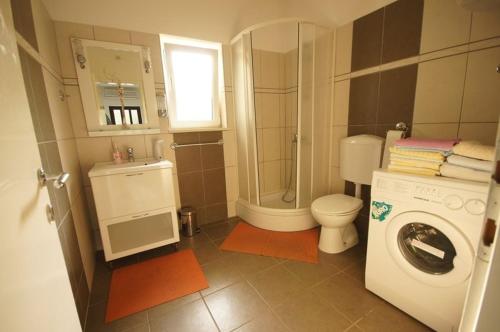 een kleine badkamer met een toilet en een wasmachine bij Apartments Viganj (22) in Viganj