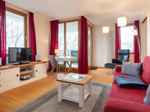 uma sala de estar com um sofá vermelho e uma televisão em Kaiservillen Heringsdorf - Ferienwohnung mit 1 Schlafzimmer und Balkon D233 em Heringsdorf