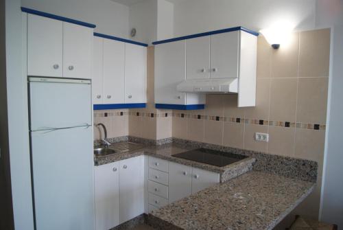 a kitchen with white cabinets and a refrigerator at Apartamentos Los Saltos in La Restinga