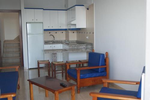 een keuken met blauwe stoelen, een tafel en een aanrecht bij Apartamentos Los Saltos in La Restinga