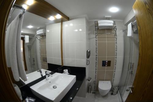 a bathroom with a sink and a toilet and a mirror at NK Hotel in Izmir