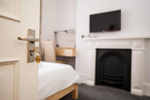 a bedroom with a bed and a fireplace with a flat screen tv at Rewley House University of Oxford in Oxford