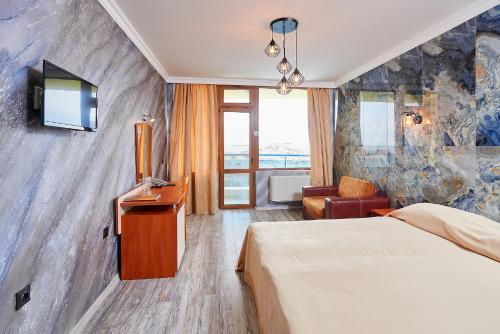 a hotel room with a bed and a tv on a wall at Petar and Pavel Hotel & Relax Center in Pomorie