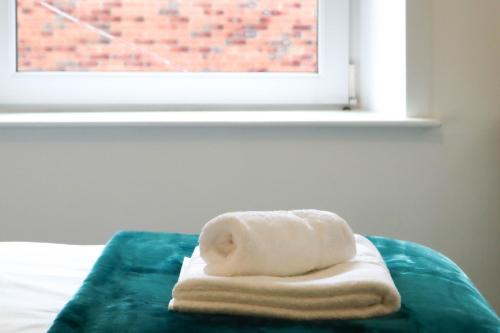 a stack of towels sitting on a bed in front of a window at Largs Coastal Apartment in Largs