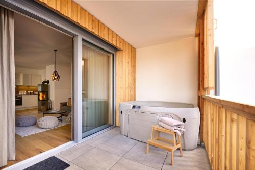 a room with a hot tub and a chair in a room at die Tauplitz Lodges - Alm Lodge A5 by AA Holiday Homes in Tauplitz