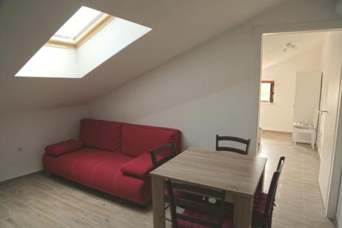 ein Wohnzimmer mit einem roten Sofa und einem Tisch in der Unterkunft Apartment in Susak with air conditioning, W-LAN (3865-6) in Susak