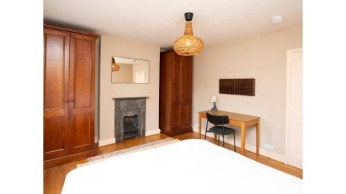 a bedroom with a bed and a desk and a chandelier at Stunning, Brand New 3BR Home - Central Oxford - Pass the Keys in Oxford