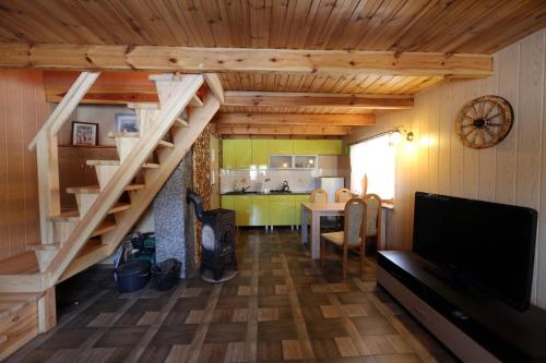 een woonkamer met een trap en een keuken bij Drewniany domek Żurawi Trakt in Ząbrsko Dolne