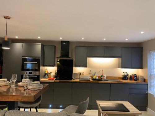 a kitchen with black cabinets and a wooden table at The Mews Cottage, with parking, Yarm in Yarm