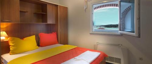 諾瓦的住宿－Apartment in Novalja with sea view, terrace, air conditioning, Wi-Fi (3565-2)，一间卧室配有一张带色彩缤纷枕头的床和窗户。