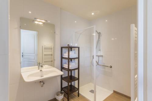 a white bathroom with a sink and a shower at La Ferme de Presles in Menainville