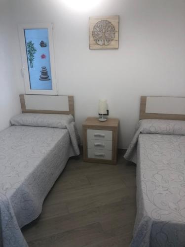 a bedroom with two beds and a dresser and a picture at Maravillosa Cala in Calahonda