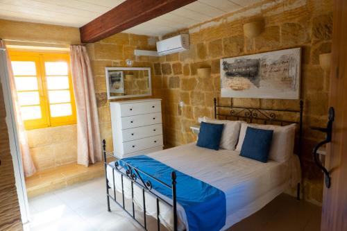 a bedroom with a bed with blue pillows at Prickly Pear Holiday Home No. 4 in San Lawrenz