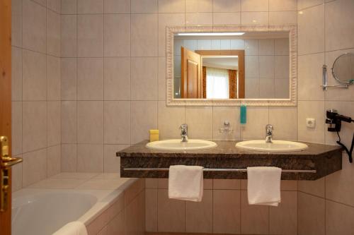 a bathroom with two sinks and a tub and a mirror at Alpenresidenz Trisanna in Ischgl
