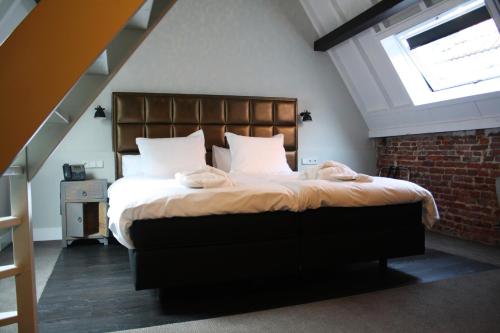 a bedroom with a large bed with a window at Hotel 't Keershuys in Den Bosch