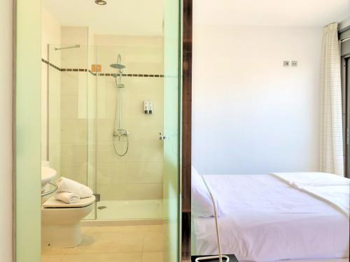 a bathroom with a shower and a bed and a toilet at Cofradia Penthouse in Alcudia