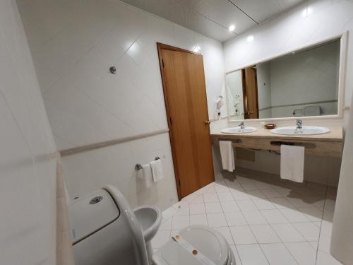 La salle de bains est pourvue de toilettes, d'un lavabo et d'un miroir. dans l'établissement Hotel Cabecinho, à Anadia