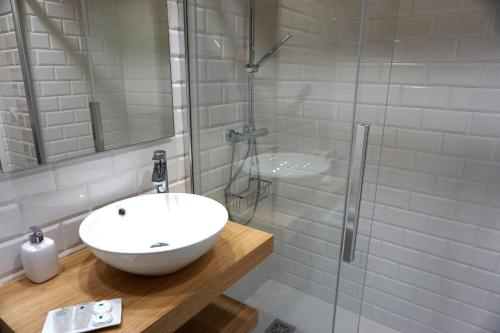 uma casa de banho branca com um lavatório e um chuveiro em Apartamentos Turísticos El Peñón em Tapia de Casariego