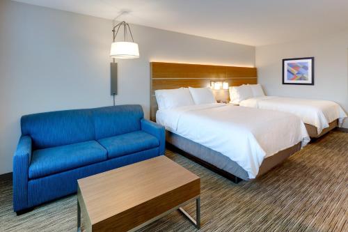 a hotel room with two beds and a blue couch at Holiday Inn Express & Suites - Middletown - Goshen by IHG in Middletown