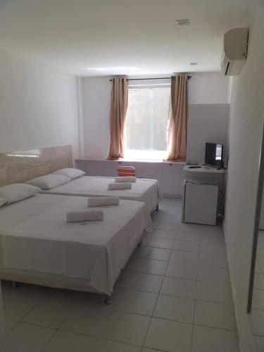 a bedroom with two beds and a window at Pousada Praia De Guarajuba in Guarajuba