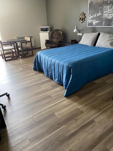 um quarto com uma cama azul e piso em madeira em Motel Populaire em Trois-Rivières