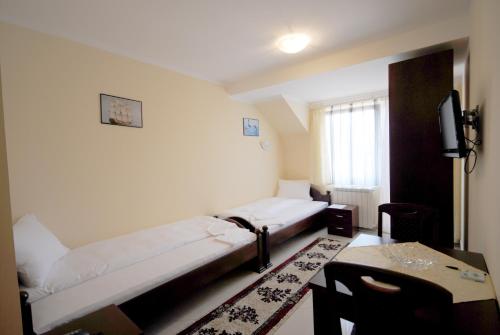 Habitación con 2 camas, mesa y TV. en Villa Ana, en Gornja Trepča