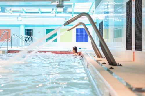a woman in an indoor pool with a water slide at Victoria Terme Hotel in Tivoli Terme