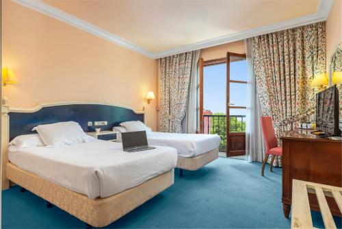 um quarto de hotel com 2 camas e uma secretária com um computador portátil em Hospedium Hotel Blu Sondika em Sondika