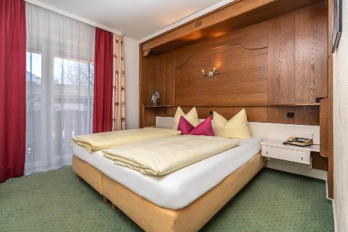 a bedroom with a large white bed with pink pillows at Hotel Sonnenspitz *** in Kochel