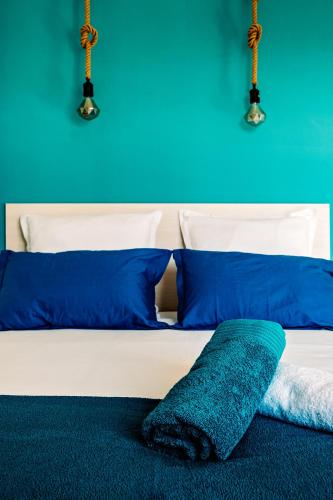 a white bed with blue pillows and a blue wall at La Maison Fratelli in Hyères