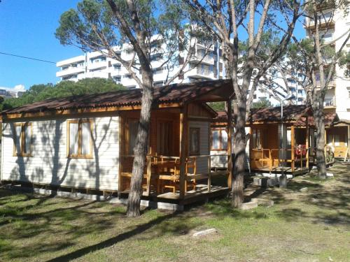 Cabaña pequeña con árboles frente a un edificio en Camping Sabanell en Blanes