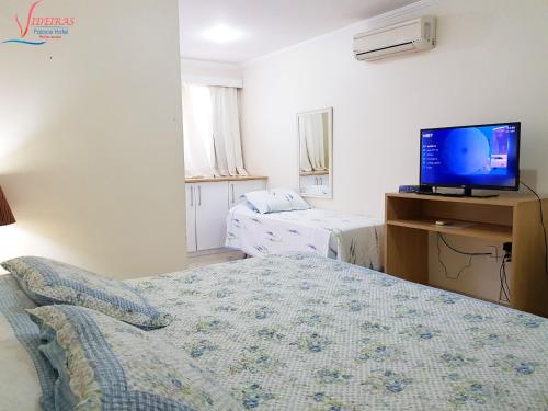 a bedroom with two beds and a tv on a desk at Videiras Palace Hotel in Cachoeira Paulista